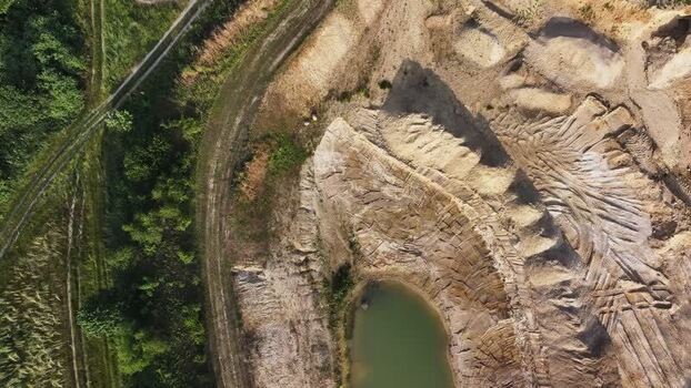 Aerial view of a sand quarry with a small pond in Germany.