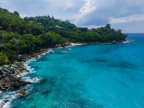 Aerial view of the turquoise sea meeting the rugged coastline lush green hills rolling down to the shore Vista do Mar Mahe Island Seychelles. Aerial view of the turquoise sea meeting the rugged coastline lush green hills rolling down to the shore Vista do Mar Mahe Island Seychelles.