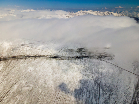 Aerial view of Babusar Pass winding through snow covered mountain slopes under a thick layer of white clouds Babusar KPK Pakistan. Aerial view of Babusar Pass winding through snow covered mountain slopes under a thick layer of white clouds Babusar KPK Pakistan.