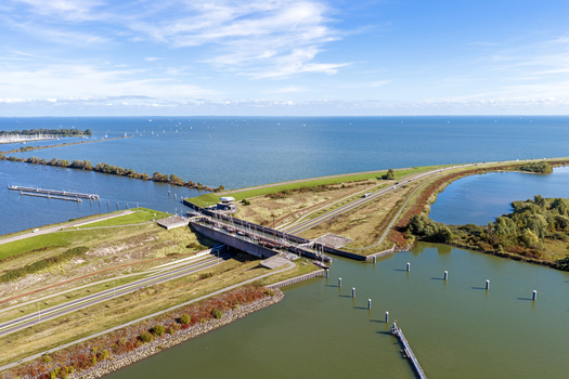 Aerial view of Naviduct Krabbersgat featuring the lock system and surrounding dikes with calm water and a clear blue sky in Lelystad Flevoland Netherlands. Aerial view of Naviduct Krabbersgat featuring the lock system and surrounding dikes with calm water and a clear blue sky in Lelystad Flevoland Netherlands.