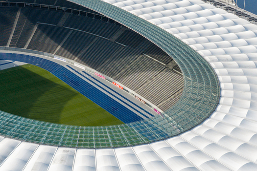 Berlin Germany 26 September 2026 Aerial view of Olympiastadion Berlin with its iconic curved roof structure blue running track and green pitch under bright daylight.