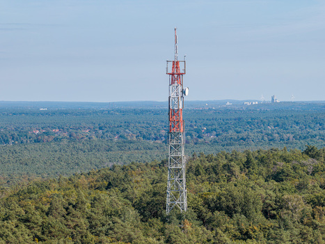 Aerial view of the Muggelberge radio antenna tower rising above the dense forest canopy in Berlin Berlin Germany. Aerial view of the Muggelberge radio antenna tower rising above the dense forest canopy in Berlin Berlin Germany.