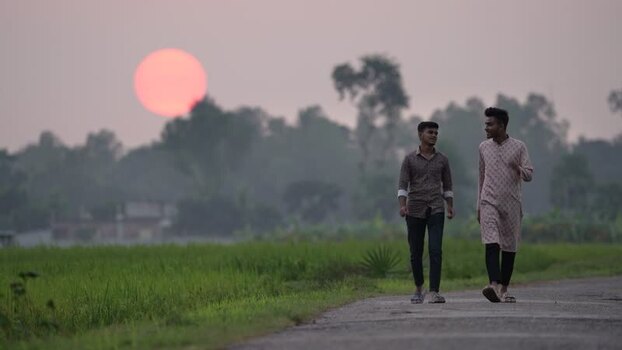 View of two men walking on a rural road at sunset Bangladesh. View of two men walking on a rural road at sunset Bangladesh.