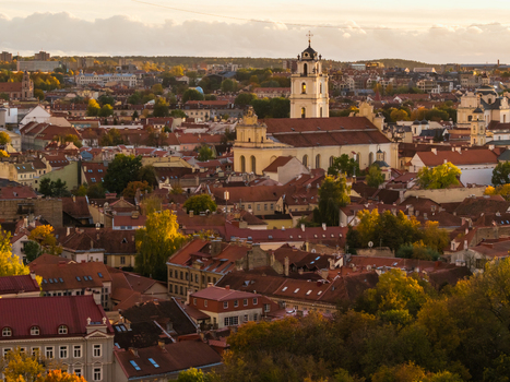 Aerial view of warm sunlight bathes the red tiled roofs and the iconic bell tower of St. John s Church stands tall against the skyline Vilnius Lithuania. Aerial view of warm sunlight bathes the red tiled roofs and the iconic bell tower of St. John s Church stands tall against the skyline Vilnius Lithuania.