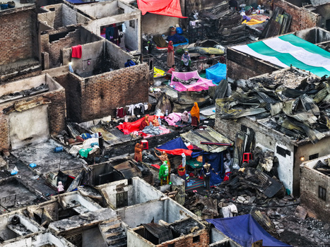 Aerial view of Korail Basti showing fire damaged structures makeshift shelters with colorful tarps and people navigating the ruins in Dhaka Dhaka Division Bangladesh.