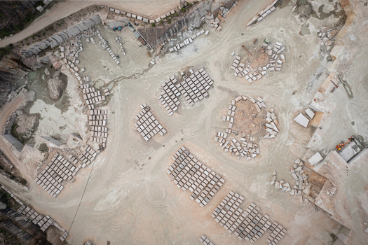 Aerial view of Cantera Porrino granite quarry with organized stacks of cut stone blocks dusty ground and heavy machinery in O Porrino Pontevedra Spain. Aerial view of Cantera Porrino granite quarry with organized stacks of cut stone blocks dusty ground and heavy machinery in O Porrino Pontevedra Spain.