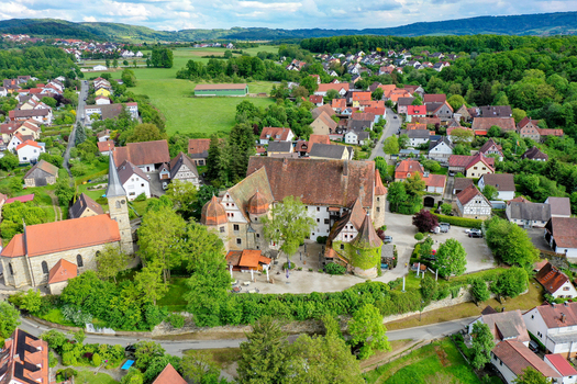 Aerial view of Schloss Wiesenthau and the village church surrounded by lush green trees and traditional houses in Wiesenthau Bayern Germany. Aerial view of Schloss Wiesenthau and the village church surrounded by lush green trees and traditional houses in Wiesenthau Bayern Germany.