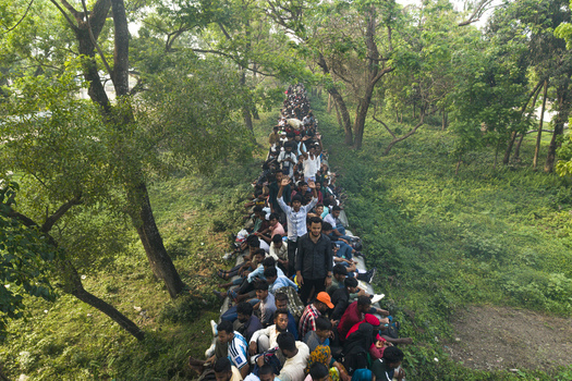 Dhaka Bangladesh 27 March 2026 Aerial view of a vibrant crowd of people gathered on a train surrounded by lush green trees and vegetation. Dhaka Bangladesh 27 March 2026 Aerial view of a vibrant crowd of people gathered on a train surrounded by lush green trees and vegetation.
