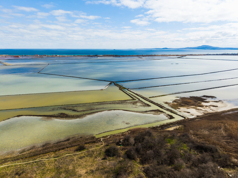 Aerial view of the colorful salt pans of Lake Atanasovsko with geometric basins and the Black Sea on the horizon in Burgas Burgas Bulgaria. Aerial view of the colorful salt pans of Lake Atanasovsko with geometric basins and the Black Sea on the horizon in Burgas Burgas Bulgaria.