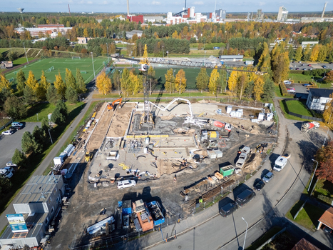 Oulu Finland 25 September 2026 Aerial view of construction site with a tower crane concrete pump and heavy machinery on a building plot surrounded by trees and urban infrastructure.