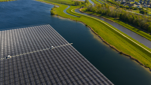 Aerial view of a large floating solar farm on a lake with green grassy banks and a winding canal in Zwolle Overijssel Netherlands. Aerial view of a large floating solar farm on a lake with green grassy banks and a winding canal in Zwolle Overijssel Netherlands.