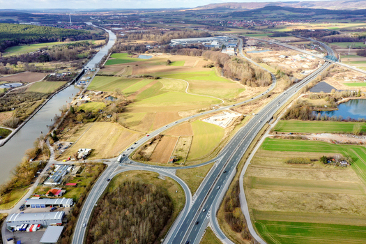 Aerial view of the highway interchange and the Main Donau Kanal canal surrounded by green fields and industrial areas in Forchheim Bavaria Germany. Aerial view of the highway interchange and the Main Donau Kanal canal surrounded by green fields and industrial areas in Forchheim Bavaria Germany.