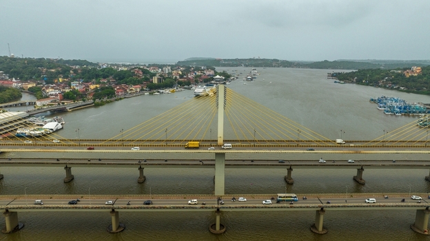 Aerial view of Atal Setu Goa a cable stayed bridge spanning the Mandovi River with traffic flowing across surrounded by the cityscape of Panaji Goa India.