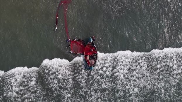 Aerial view of fishermen pulling a red net into a boat Bangladesh. Aerial view of fishermen pulling a red net into a boat Bangladesh.