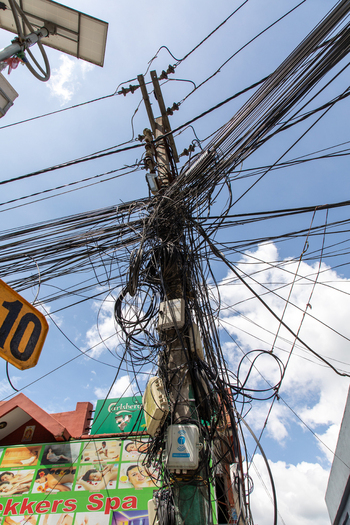 Pokhara Gandaki Province Nepal 31 July 2026 View of a utility pole heavily congested with a complex web of tangled electrical wires and cables against a bright blue sky.