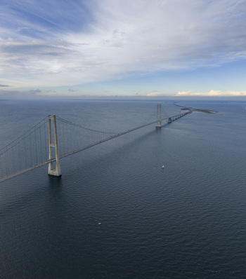 Aerial view of the Great Belt Bridge spanning across the blue sea under a soft cloudy sky in Denmark. Aerial view of the Great Belt Bridge spanning across the blue sea under a soft cloudy sky in Denmark.