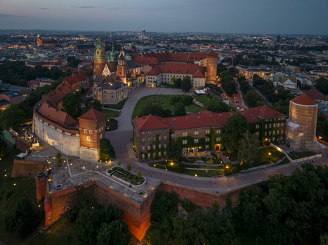 Aerial view of Wawel Castle featuring historic fortifications red tile roofs and a central courtyard illuminated at dusk in Krakow Lesser Poland Voivode Poland. Aerial view of Wawel Castle featuring historic fortifications red tile roofs and a central courtyard illuminated at dusk in Krakow Lesser Poland Voivode Poland.