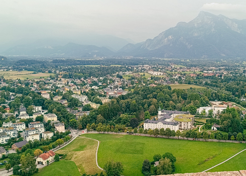 View of the historic city of Salzburg with green meadows trees and traditional architecture nestled against the backdrop of the Austrian Alps in Salzburg Salzburg Austria. View of the historic city of Salzburg with green meadows trees and traditional architecture nestled against the backdrop of the Austrian Alps in Salzburg Salzburg Austria.