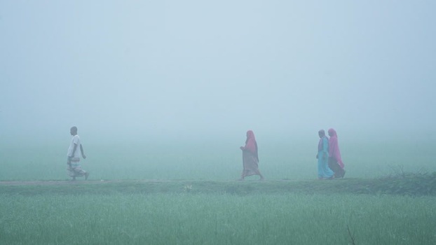 View of people walking through a foggy field in Bogura Bangladesh.