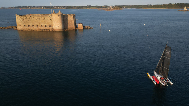 Aerial view of the imposing stone fortress stands sentinel on a small island as a sailboat glides through the serene waters Plouezoc h Bretagne France.