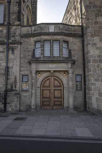 View of the historic entrance to the Durham University Library featuring stone masonry arched wooden doors and leaded glass windows in Durham England United Kingdom. View of the historic entrance to the Durham University Library featuring stone masonry arched wooden doors and leaded glass windows in Durham England United Kingdom.