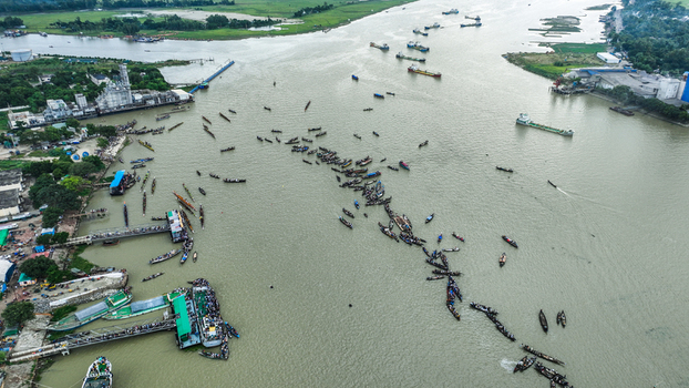 Baghabari Rajshahi Division Bangladesh 20 August 2022 Aerial view of numerous wooden boats gathered on the river near the port with industrial facilities and green landscape.