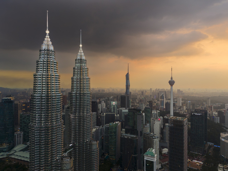 Kuala Lumpur Malaysia 11 March 2026 Aerial view of the Petronas Twin Towers and the city skyline under a dramatic sunset sky with dark storm clouds.