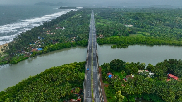 Aerial view of the bridge crossing the river near Galgibaga Beach surrounded by lush tropical palm trees and the coastline in Canacona Goa India.