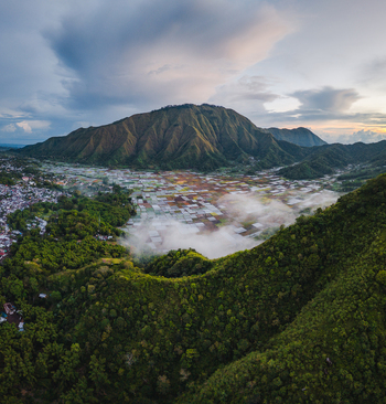Aerial view of the Sembalun agricultural basin nestled at the foothills of Mount Rinjani with patchwork fields and morning mist in Sembalun West Nusa Tenggara Indonesia. Aerial view of the Sembalun agricultural basin nestled at the foothills of Mount Rinjani with patchwork fields and morning mist in Sembalun West Nusa Tenggara Indonesia.