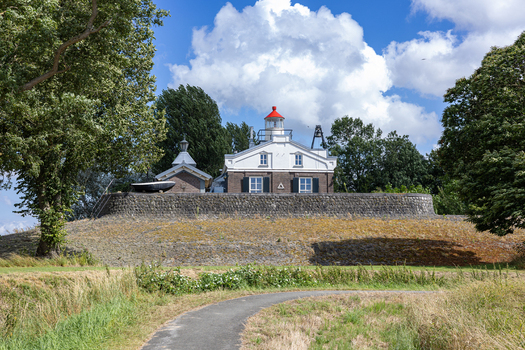 View of Lichtwachterswoning Oud Kraggenburg historic lighthouse keeper s house on a stone mound surrounded by green trees under a blue sky in Kraggenburg Flevoland Netherlands. View of Lichtwachterswoning Oud Kraggenburg historic lighthouse keeper s house on a stone mound surrounded by green trees under a blue sky in Kraggenburg Flevoland Netherlands.