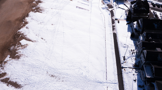 Aerial view of a snow covered beach and coastal residential area with footprints in the snow and houses along the shoreline in Manasquan New Jersey United States. Aerial view of a snow covered beach and coastal residential area with footprints in the snow and houses along the shoreline in Manasquan New Jersey United States.