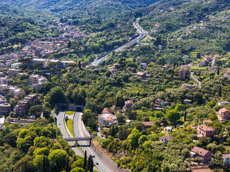 Aerial view of the A12 highway winding through lush green hills and residential areas with tunnels and overpasses Genova Liguria Italy. Aerial view of the A12 highway winding through lush green hills and residential areas with tunnels and overpasses Genova Liguria Italy.