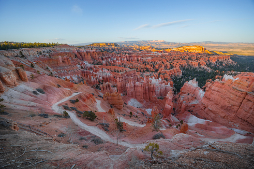 View of the iconic red rock hoodoos and winding trails of Bryce Canyon National Park at golden hour in Utah United States.