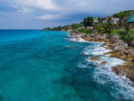 Aerial view of turquoise waters crash against the rocky shores where lush greenery meets the azure sky Vista do Mar Mahe Island Seychelles. Aerial view of turquoise waters crash against the rocky shores where lush greenery meets the azure sky Vista do Mar Mahe Island Seychelles.