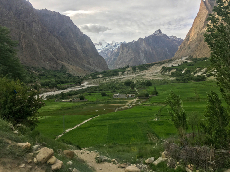View of the lush green fields of the Hushe River Valley surrounded by towering mountains under a cloudy sky in Saling Gilgit Pakistan. View of the lush green fields of the Hushe River Valley surrounded by towering mountains under a cloudy sky in Saling Gilgit Pakistan.