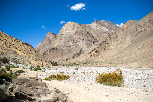 View of K2 Base Camp surrounded by rugged mountain peaks rocky terrain and sparse vegetation under a clear blue sky in Ghakhar Gilgit Pakistan. View of K2 Base Camp surrounded by rugged mountain peaks rocky terrain and sparse vegetation under a clear blue sky in Ghakhar Gilgit Pakistan.