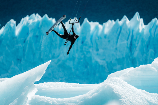 View of a kitesurfer performing an aerial trick in front of the massive blue ice walls of the Perito Moreno Glacier Perito Moreno Santa Cruz Province Argentina. View of a kitesurfer performing an aerial trick in front of the massive blue ice walls of the Perito Moreno Glacier Perito Moreno Santa Cruz Province Argentina.