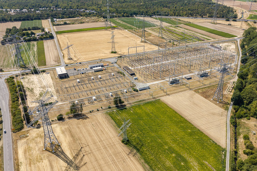 Aerial view of Amprion Umspannwerk electrical substation surrounded by agricultural fields power lines and transmission towers in Pfungstadt Hessen Germany.
