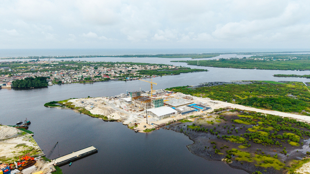 Aerial view of a construction site on a peninsula in Satellite Town featuring a crane unfinished buildings and surrounding wetlands and water in Lagos Lagos Nigeria.