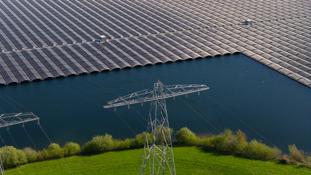 Aerial view of floating solar panels on a lake with high voltage power lines and green vegetation Zwolle Overijssel Netherlands. Aerial view of floating solar panels on a lake with high voltage power lines and green vegetation Zwolle Overijssel Netherlands.