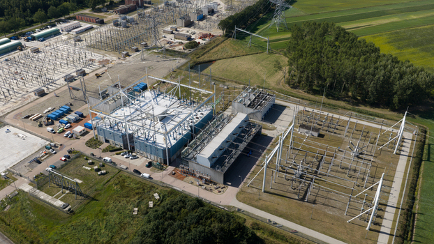 Aerial view of the high voltage substation in Meeden featuring electrical infrastructure transformers and power lines surrounded by green fields and trees in Meeden Groningen Netherlands.
