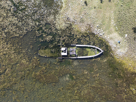 Aerial view of the sunken boat Anija e mbytur resting in the shallow algae covered waters near the shore in Shiroka Shkoder County Albania. Aerial view of the sunken boat Anija e mbytur resting in the shallow algae covered waters near the shore in Shiroka Shkoder County Albania.