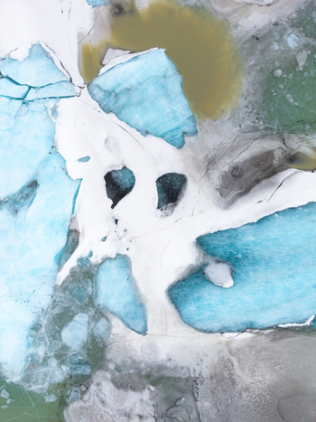 Aerial view of glacial ice showing vibrant turquoise hues against stark white snow formations with dark pools adding depth &Ouml;r&aelig;fi Iceland.