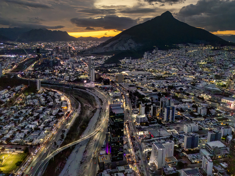 Aerial view of the city of Monterrey at night featuring illuminated skyscrapers busy highways and the prominent Cerro de la Silla mountain in Monterrey Nuevo Leon Mexico. Aerial view of the city of Monterrey at night featuring illuminated skyscrapers busy highways and the prominent Cerro de la Silla mountain in Monterrey Nuevo Leon Mexico.