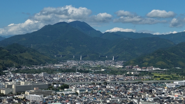 Aerial view of the cityscape of Shizuoka featuring the dense urban layout of Aoi and Suruga Wards nestled against lush green mountains under a clear blue sky in Shizuoka Shizuoka Japan.