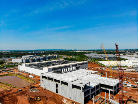 Aerial view of a large data center construction site featuring concrete structures tall cranes and heavy machinery set against a clear blue sky in Ashburn Virginia United States. Aerial view of a large data center construction site featuring concrete structures tall cranes and heavy machinery set against a clear blue sky in Ashburn Virginia United States.
