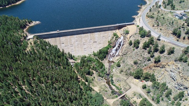 Aerial view of Barker Meadow Reservoir and concrete dam with a waterfall cascading down the slope surrounded by pine forests and a winding road in Boulder County Colorado United States. Aerial view of Barker Meadow Reservoir and concrete dam with a waterfall cascading down the slope surrounded by pine forests and a winding road in Boulder County Colorado United States.