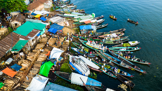 Rangamati Chittagong Division Bangladesh 19 October 2022 Aerial view of the bustling riverbank with wooden boats timber piles colorful shelters and people in the port area.