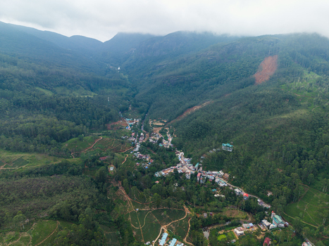 Aerial view of the village of Nallathanniya nestled in a lush green valley surrounded by tea plantations and misty mountains Nallathanniya Central Province Sri Lanka. Aerial view of the village of Nallathanniya nestled in a lush green valley surrounded by tea plantations and misty mountains Nallathanniya Central Province Sri Lanka.