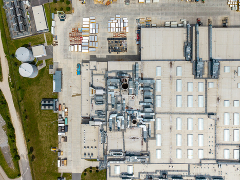 Aerial view of an industrial facility with a large flat roof ventilation systems storage areas and circular tanks in Zebrak Central Bohemian Region Czechia. Aerial view of an industrial facility with a large flat roof ventilation systems storage areas and circular tanks in Zebrak Central Bohemian Region Czechia.